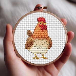 May include: A cross-stitch embroidery hoop with a detailed rooster design. The rooster has a red comb and wattle, with brown and orange feathers. The embroidery is set in a wooden hoop, ideal for home decor or craft projects.