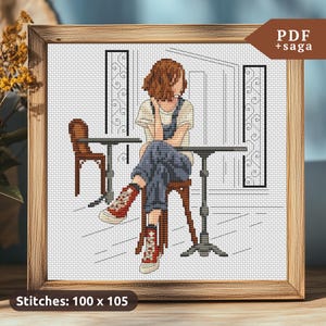 May include: Cross stitch pattern of a person sitting at a table in a cafe. The person is wearing jeans and a white shirt. The pattern is 100 stitches wide by 105 stitches high.