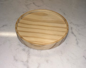May include: A round wooden tray with a natural wood finish. The tray has a slightly raised edge and is perfect for serving snacks or drinks.