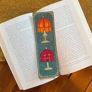 Könnte beinhalten: Ein blaugrünes Lesezeichen mit einem Kreuzstich-Design aus drei Lampen. Die Lampen sind rot, orange und gelb mit weißen Sockeln. Das Lesezeichen ist eine großartige Möglichkeit, um Ihren Platz in einem Buch zu markieren.