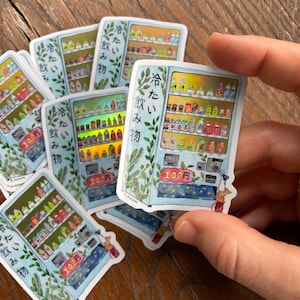 May include: A set of six stickers featuring a blue vending machine with a variety of colorful drinks and snacks. The vending machine has a sign that reads "Cold Drinks" in Japanese. Each sticker has a different design and features a small animal.