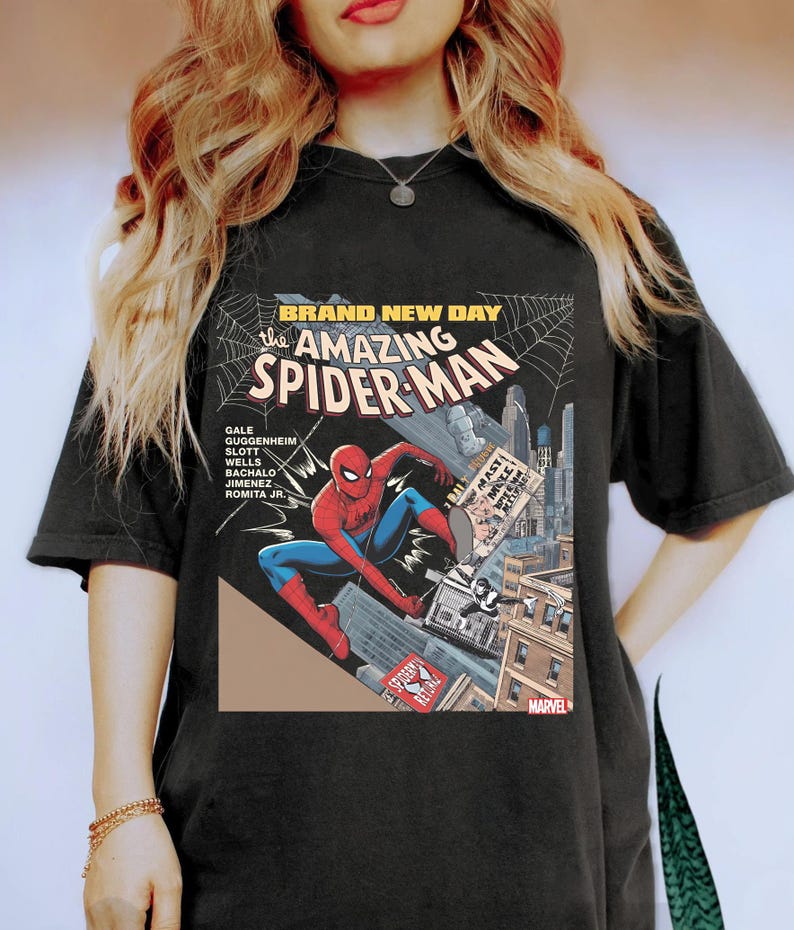 May include: Black t-shirt featuring a comic book cover design of Spider-Man. The graphic includes the text "BRAND NEW DAY" and "the AMAZING SPIDER-MAN". The superhero is depicted in a dynamic pose, with a cityscape backdrop and the Marvel logo.
