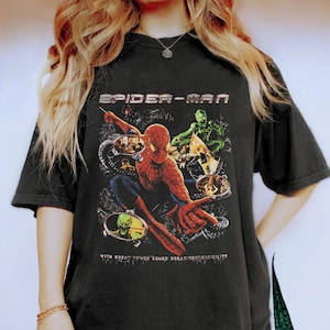 Puede incluir: Camiseta negra con un gr&aacute;fico de Spider-Man. El dise&ntilde;o incluye a Spider-Man en acci&oacute;n, el Duende Verde y el texto "SPIDER-MAN" encima de la imagen. Debajo de la imagen est&aacute; el texto "WITH GREAT POWER COMES GREAT RESPONSIBILITY."
