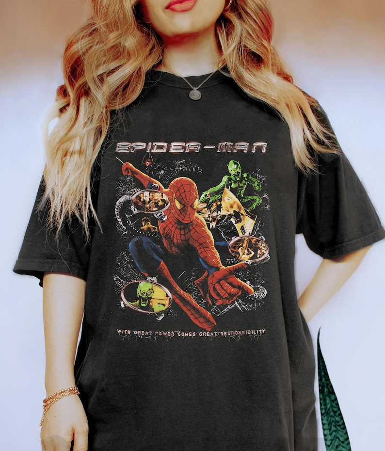 Puede incluir: Camiseta negra con un gr&aacute;fico de Spider-Man. El dise&ntilde;o incluye a Spider-Man en acci&oacute;n, el Duende Verde y el texto "SPIDER-MAN" encima de la imagen. Debajo de la imagen est&aacute; el texto "WITH GREAT POWER COMES GREAT RESPONSIBILITY."