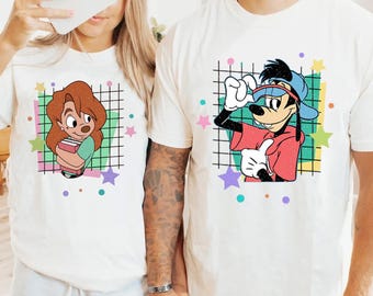 May include: A white t-shirt with a cartoon image of Goofy wearing a blue hat and red shirt. The image is surrounded by a grid pattern and colorful stars. The t-shirt is a great gift for fans of Disney.