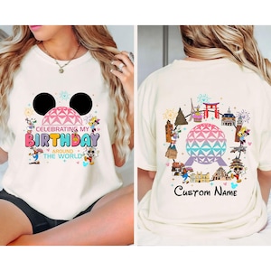 Op de afbeelding: Wit T-shirt met een kleurrijke afbeelding van Mickey Mouse-oren en de tekst "Celebrating My Birthday Around The World". De achterkant van het shirt heeft een kleurrijke afbeelding van de Epcot-bol en verschillende Disney-figuren.