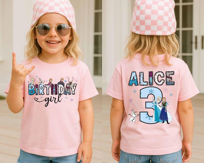 May include: A light pink short-sleeved t-shirt featuring a graphic print. The front displays the text "BIRTHDAY girl" with cartoon characters. The back shows the name "ALICE" above a large number "3" and additional cartoon character graphics.