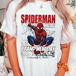 Puede incluir: Camiseta blanca con un dise&ntilde;o de Spider-Man en una telara&ntilde;a, con el texto rojo "SPIDERMAN". El dise&ntilde;o incluye las frases "WITH GREAT POWER COMES GREAT RESPONSIBILITY" y "BRAND NEW DAY".