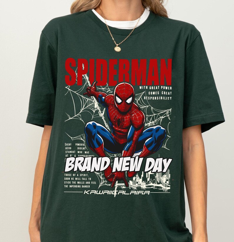 Puede incluir: Camiseta verde oscuro con un dise&ntilde;o de Spider-Man en una telara&ntilde;a, texto "SPIDERMAN" en rojo y las frases "WITH GREAT POWER COMES GREAT RESPONSIBILITY" y "BRAND NEW DAY".