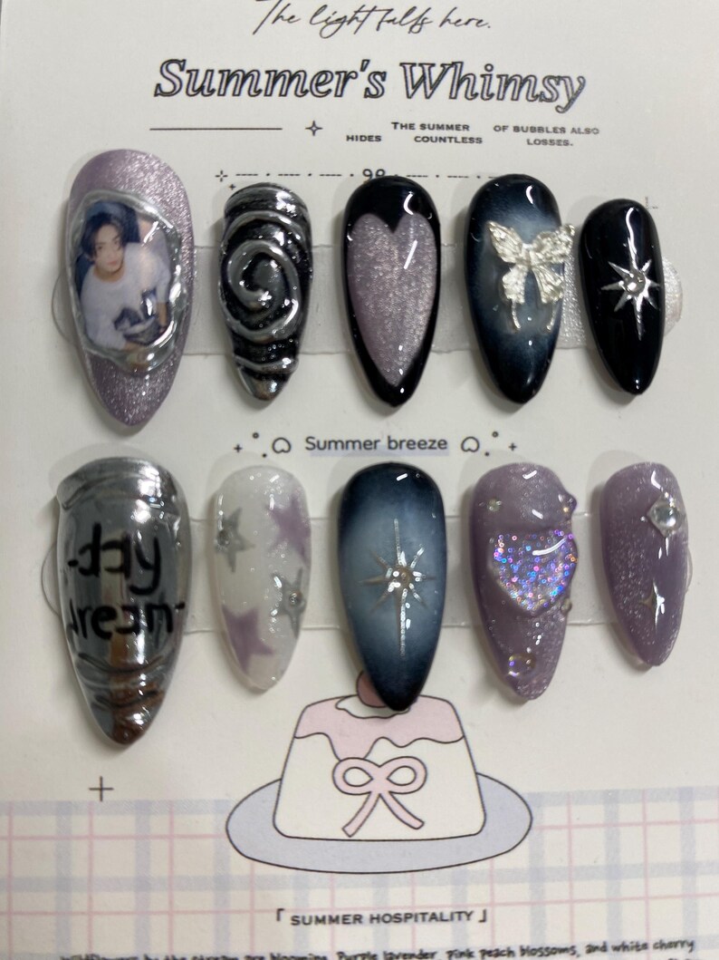 May include: A collection of ten artificial nails with diverse designs. The nails showcase silver, black, and purple hues, adorned with glitter, stars, and a bow. Some nails have text or images. The text "Summer's Whimsy" is at the top of the image.