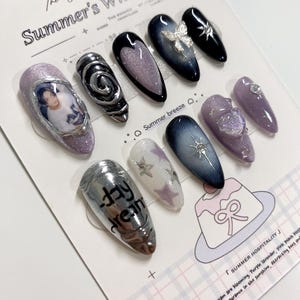 May include: A selection of artificial nails with diverse designs. Some nails are silver chrome, glitter, and artwork. Other nails feature butterfly, star, and swirl designs. The text "day dream" is visible on one nail. The theme is "Summer's Whimsy".