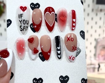 May include: A set of ten Valentine's Day themed press-on nails with various designs. The nails feature red, white, and black hearts, the words "If You Say", and "XO" written on them.