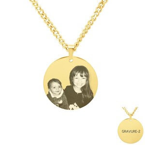 Può includere: Collana d'oro con un ciondolo rotondo che presenta una foto in bianco e nero di due bambini. Il ciondolo ha una superficie liscia e lucida.