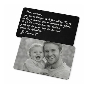 Puede incluir: Dos tarjetas rectangulares. La tarjeta superior es negra con escritura blanca que dice "Mon amour, Je serai toujours à tes côtés... Je t'aime ". La tarjeta inferior tiene una foto en blanco y negro de un hombre y un bebé sonriendo.