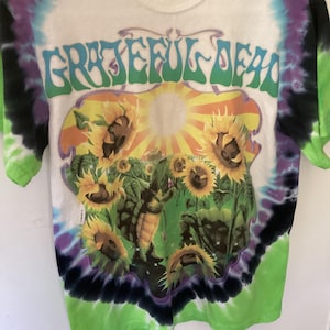 May include: A white ceramic mug with a black handle and the text "But First, Coffee" in a black, handwritten-style font. The mug is on a white surface.