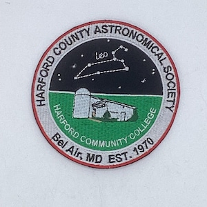 May include: A circular embroidered patch featuring a black night sky with the Leo constellation and a white observatory building on a green field. The border text reads Harford County Astronomical Society, Harford Community College, Bel Air, MD EST. 1970.