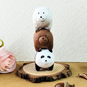 Può includere: Una pila di tre figurine di legno di orsi dei cartoni animati. L'orso in basso è bianco e nero con gli occhi blu. L'orso in mezzo è marrone con il naso marrone e gli occhi neri. L'orso in alto è bianco con il naso nero e gli occhi neri. Gli orsi sono impilati su una base di legno.