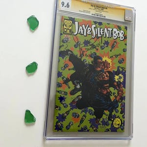 May include: A graded comic book titled "Jay & Silent Bob #4" with a 9.6 grade. The cover features a colorful illustration of the characters. Three pieces of green sea glass are arranged on the left side of the image.