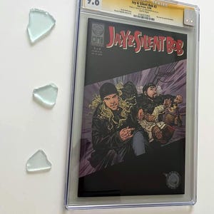 May include: A graded comic book titled "Jay & Silent Bob #3" with a 9.6 grade. The cover art features two characters in a comic book style. The comic is encased in a clear protective case, with three pieces of sea glass.