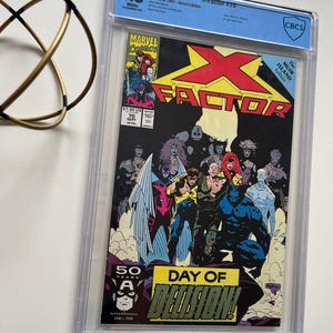 Puede incluir: Un cómic calificado, X-Factor #70, con una portada vibrante con múltiples personajes y el texto "DAY OF DECISION!". El cómic está encerrado en un soporte protector transparente con una calificación de 9.8.