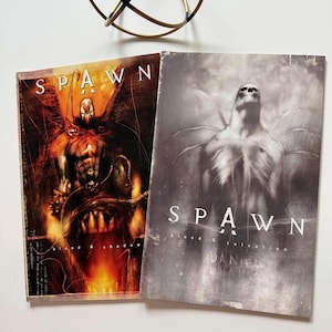 May include: Two Spawn comic books. One cover features a fiery image of Spawn with the text "Spawn" above and "blood & shadow" below. The other cover is grayscale, with Spawn and the text "Spawn blood & salvation".