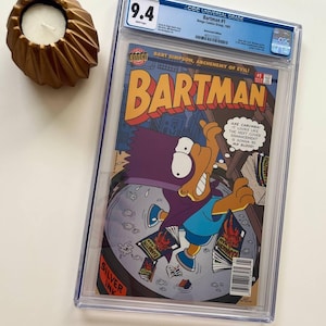 Könnte beinhalten: Ein bewertetes Comic-Buch mit dem Titel "Bartman #1" mit Bart Simpson in einem Superhelden-Kostüm. Das Comic ist in einem transparenten Schutzgehäuse mit der Note 9,4 eingeschlossen. Ein goldfarbener Kerzenhalter mit einer weißen Kerze ist ebenfalls vorhanden.