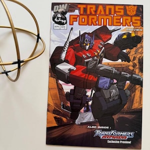 May include: A comic book cover featuring a red and blue robot, Optimus Prime, from the Transformers franchise. The cover is titled "Transformers Preview" and features the text "Also Inside: Transformers Armada Exclusive Preview!"