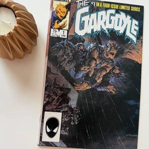 May include: A vintage Marvel comic book titled "The Gargoyle" with a June issue date. The cover features a detailed illustration of a monstrous figure in a dark, action-packed scene. A gold-colored candle holder is in the upper left corner.