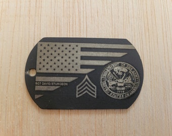 Könnte beinhalten: Schwarzer Metall-Hundeanhänger mit einer goldfarbenen amerikanischen Flagge, dem Text "SGT DAVID STURGEON", einem goldfarbenen Rangabzeichen und dem Siegel des US-amerikanischen Heeres.