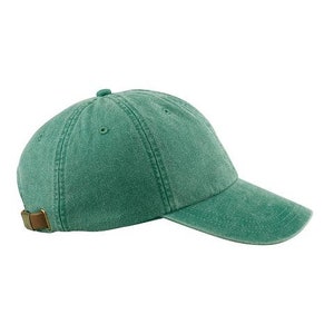 Puede incluir: Una gorra de b&eacute;isbol de algod&oacute;n verde con una correa ajustable marr&oacute;n.