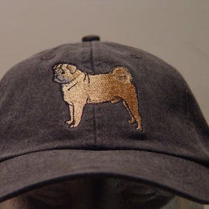 Puede incluir: Una gorra de b&eacute;isbol gris oscuro con una imagen bordada de un perro carlino.