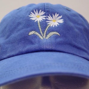 May include: A blue baseball cap with two white embroidered daisies on the front.
