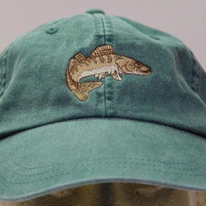 May include: A green baseball cap with an embroidered image of a fish. The fish is brown and white and has a detailed design.