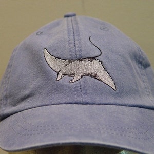 Puede incluir: Una gorra de béisbol azul claro con una imagen bordada de una manta raya en blanco y negro.