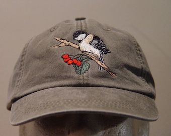 以下が含まれることがあります： 赤い実のついた枝に止まっている鳥の刺繍が施された緑色のベースボールキャップ。