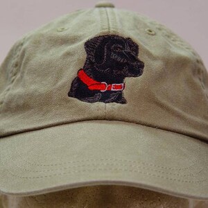 Pu&ograve; includere: Un cappello da baseball verde kaki con un labrador retriever nero ricamato che indossa un collare rosso.