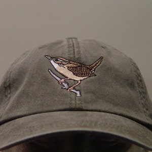 May include: A green baseball cap with an embroidered brown bird perched on a branch.