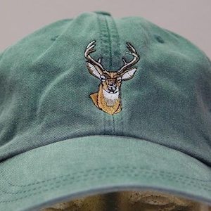 Puede incluir: Una gorra de béisbol verde con una imagen bordada de un ciervo con cuernos.