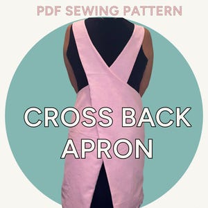 以下が含まれることがあります： 白い文字で「CROSS BACK APRON」と書かれたピンク色のクロスバックエプロン。画像には「SIZES S-XL」、「BEGINNER FRIENDLY」、「PDF SEWING PATTERN」の文字も含まれています。エプロンは黒いトップスを着た人に表示されています。