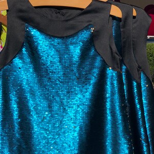 May include: A sleeveless sequined dress with a black bodice and a teal blue sequined skirt.