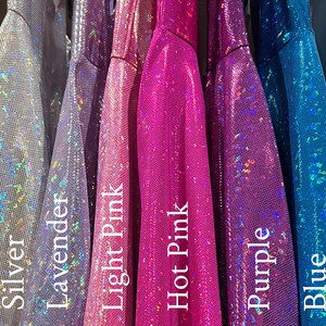May include: A close-up of six different iridescent fabrics in various colors, including silver, lavender, light pink, hot pink, purple, and blue. The fabrics are all shiny and have a sparkly texture.