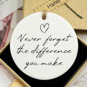 May include: White ceramic ornament with a black handwritten message that reads "Never forget the difference you make". The ornament is in a small box with a brown lid that says "Hand made".