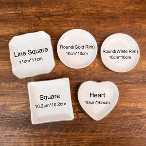 May include: Five white ceramic dishes in various shapes: a line square (11cm x 11cm), a round with a gold rim (10cm x 10cm), a round with a white rim (10cm x 10cm), a square (10.2cm x 10.2cm), and a heart (10cm x 9.5cm).