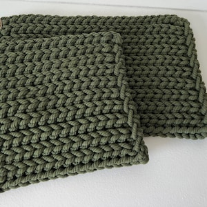 May include: Three green knitted pot holders with leather tabs. The pot holders are made of a thick, textured yarn.