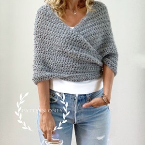 Puede incluir: Un chal gris tejido a ganchillo con un diseño de cuello en V. El chal está hecho de un hilo grueso y tiene una apariencia texturizada. Las palabras "PATTERN ONLY" son visibles en la imagen.