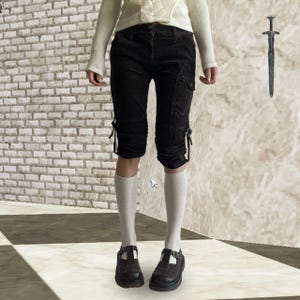 May include: Black capri pants with cargo pockets and tie details. The pants are paired with white knee-high socks and dark brown Mary Jane shoes. A white sweater is worn on top.