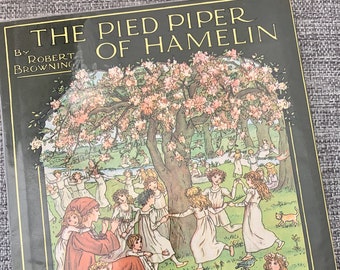 May include: The cover of a vintage children's book titled "The Pied Piper of Hamelin" by Robert Browning. The cover features an illustration by Kate Greenaway of children dancing in a forest with a piper playing a flute.