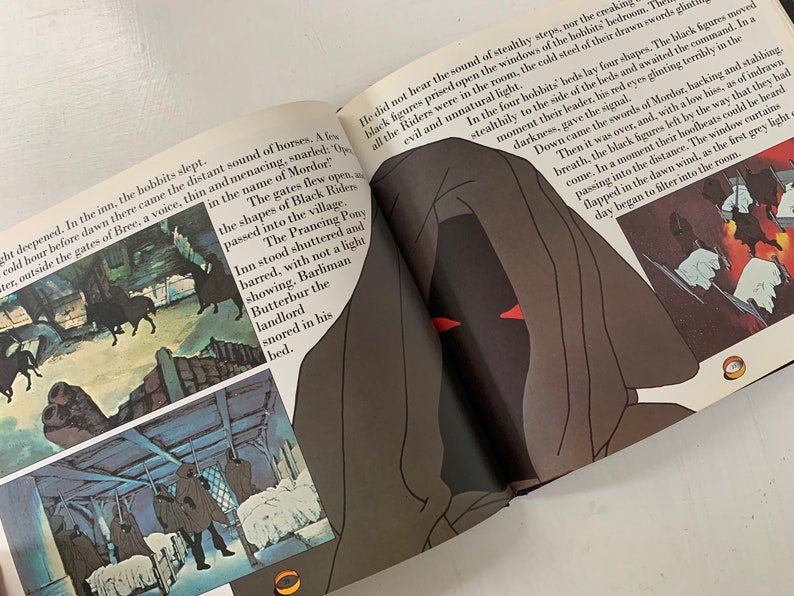 May include: A book open to a page with an illustration of a hooded figure with red eyes. The text on the page reads "The gates flew open in the name of Mordor." The illustration is in a dark, shadowy style.