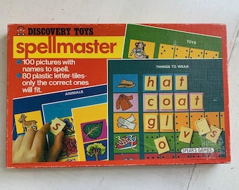 May include: Vintage Discovery Toys Spellmaster game box. The red box features the game's name and details: 100 pictures with names to spell, 80 plastic letter tiles. The game includes picture cards and letter tiles for spelling words.