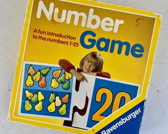 May include: A yellow box with the text "Number Game" in blue and white letters. The box has a picture of a girl holding a puzzle piece with the number 20 on it. The text "A fun introduction to the numbers 1-25" is also on the box. The box is made by Ravensburger.